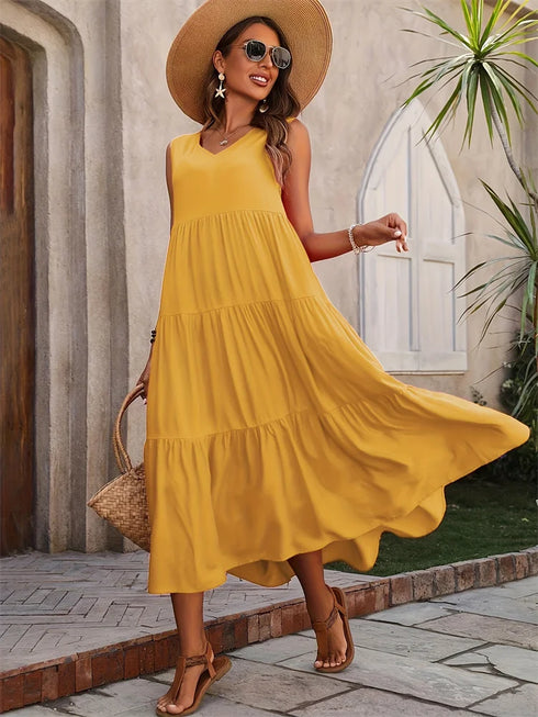 Woman in a yellow dress and sun hat standing outdoors.